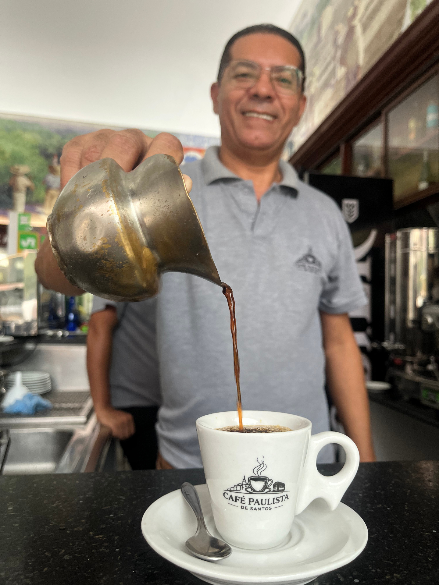 Valmir do Nascimento servindo café com a tradicional louça de prata do Café Paulista em uma xícara branca da casa