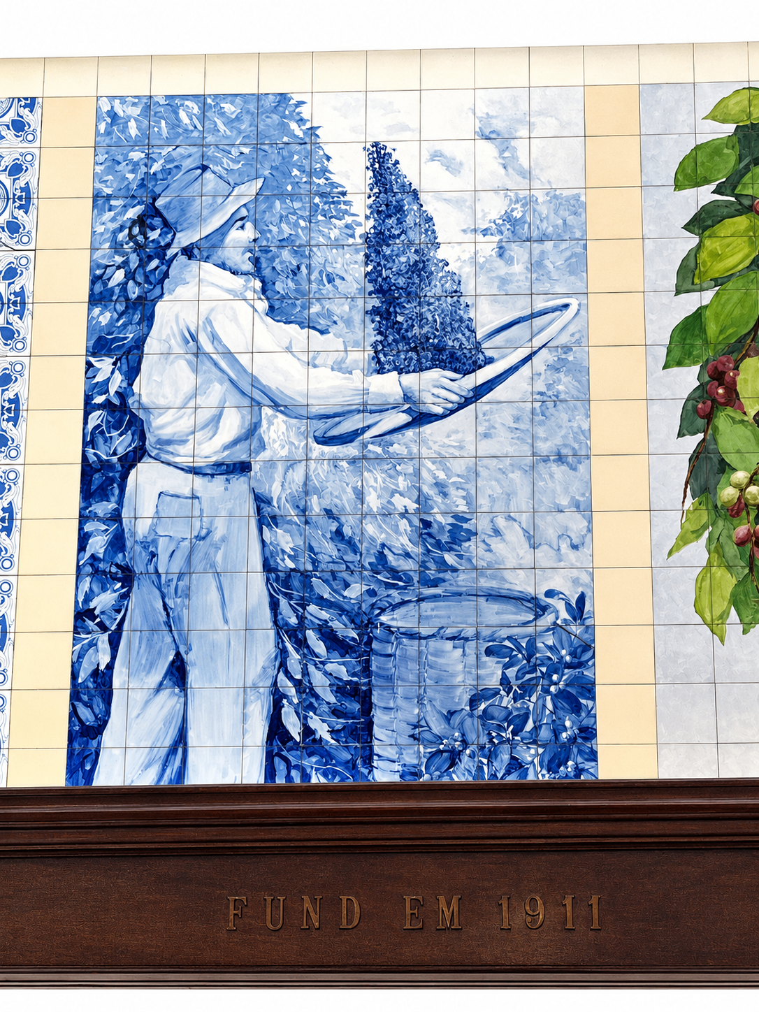 Painel pintado à mão em azulejos azuis retratando a colheita do café no Café Paulista de Santos